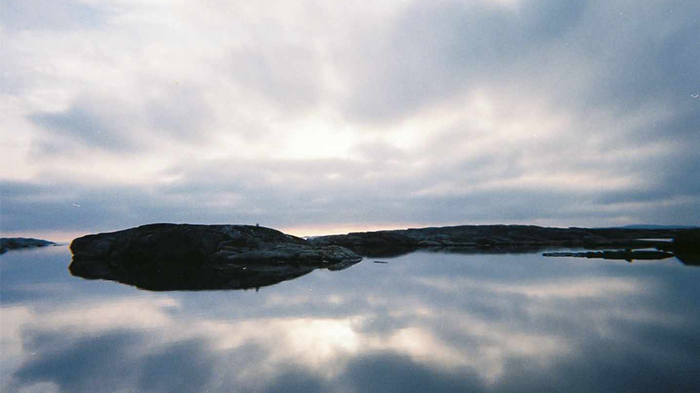 Landskap med hav og skyer som speiler seg i vannet. 