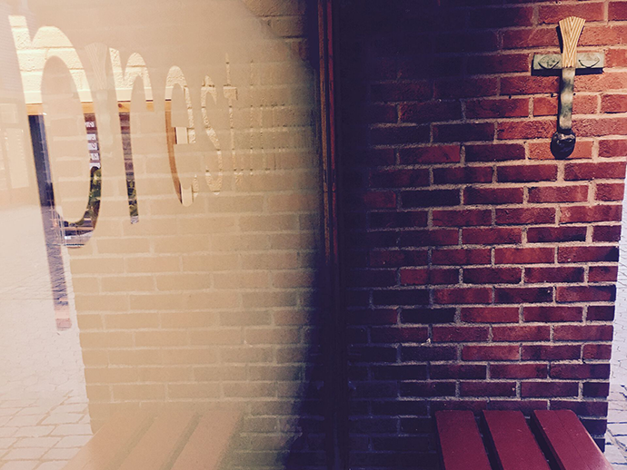 Photo of the outside of the consultation room. A cross adorns the brick wall.